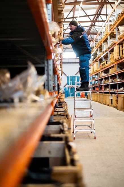 Worker on ladder in warehouse